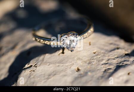 Selective closeup shot of a heart-shaped ring on a rock with a blurred background Stock Photo