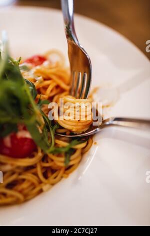 Closeup shot of tasty spaghetti with vegetables and sauce in a white plate Stock Photo