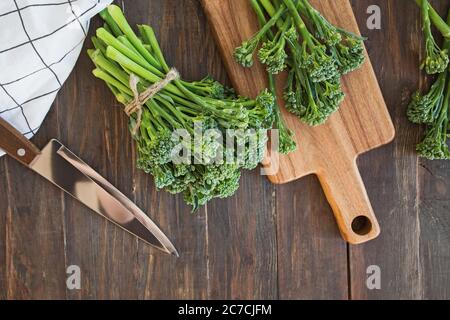 Raw green broccolini vegetable on wooden table. Stock Photo