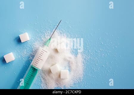 Granulated sugar, sugar cubes and syringe on blue backgroud. Stock Photo