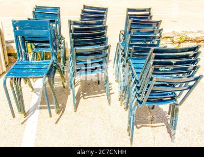 Stacked blue chairs resting outside a cafe on a sunny day. France Stock Photo