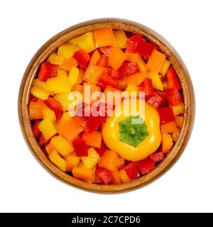 Bell pepper head and diced pods in wooden bowl. Sweet pepper, capsicum, also paprika, cut in colorful chips. Fresh yellow, orange and red fruits. Stock Photo