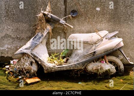 Closeup shot of a motorcycle covered with mud and dirt leaning on a wall during daytime in Japan Stock Photo