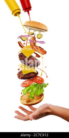 Cooking of mega burger. Flying multilayer dish with splashes on white Stock Photo