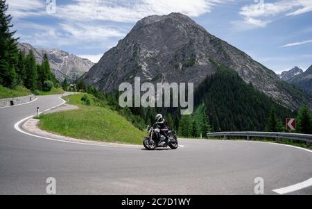 Motorcycle driver riding in Alpine road, Austria, Europe. Outdoor photography, mountain landscape. Travel and sport photography. Speed and freedom Stock Photo