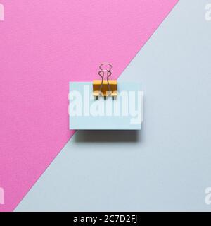 Blue memo paper, sticky notes with yellow binder clip on pink and blue background. top view, copy space Stock Photo