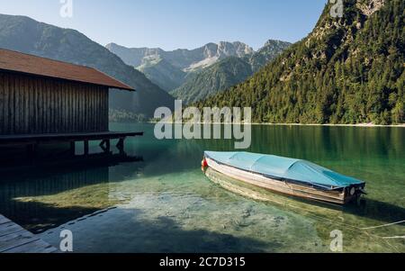 Small boat on crystal clear lake Plansee in the European Alps, in Austria at early morning sunrise Stock Photo