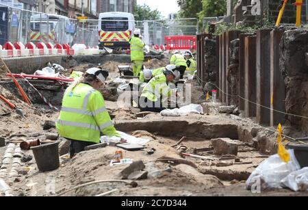 Archaeologists from the Trams to Newhaven project excavating human remains, which could date back as far as 1300, from the graves of South Leith Parish Church whose medieval graveyard extends beneath the road surface of Constitution Street, Leith. Stock Photo