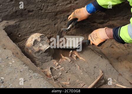 Archaeologists from the Trams to Newhaven project excavating human remains, which could date back as far as 1300, from the graves of South Leith Parish Church whose medieval graveyard extends beneath the road surface of Constitution Street, Leith. Stock Photo