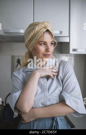 Vertical shot of an attractive female model with a headscarf posing in the kitchen Stock Photo