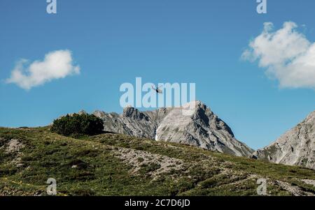 Helicopter flying over the rocky Mountains during a sunny sunset. Aerial Landscape from Austrian Alps.Panoramic nature background Stock Photo