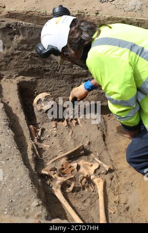 Archaeologists from the Trams to Newhaven project excavating human remains, which could date back as far as 1300, from the graves of South Leith Parish Church whose medieval graveyard extends beneath the road surface of Constitution Street, Leith. Stock Photo