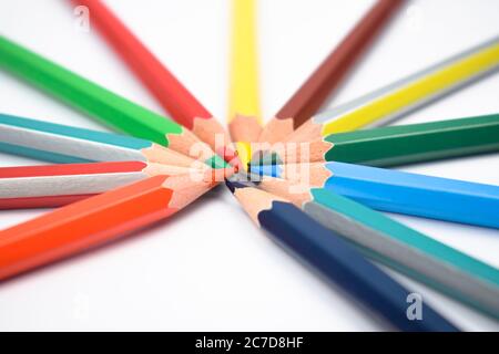 Many different colored wood pencil crayons placed on a white paper in a round circle Stock Photo