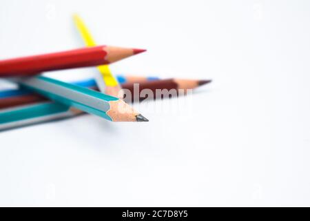 Five different colored wood pencil crayon scattered on a white paper background Stock Photo