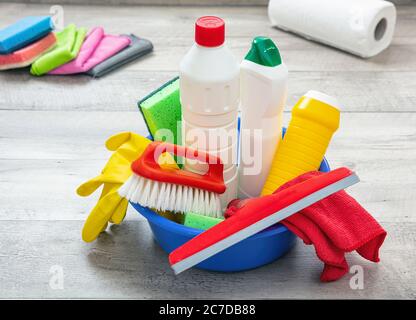 Cleaning products on the floor, home interior background. Chemical detergent bottles in a blue bowl. Domestic household or business sanitary cleaning Stock Photo