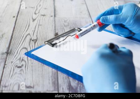 laboratory technician hand holding blood test tube and writing on paper  Stock Photo
