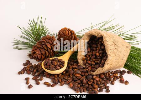 Unpeeled pine nuts in a linen bag on white background. Horizontal frame copy space. Stock Photo
