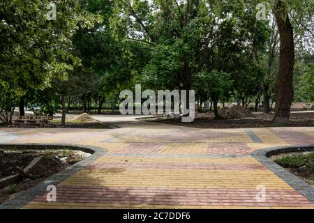 Laying colored concrete paving slabs in the park. Professional workers bricklayers are installing new tiles and paving slabs for sidewalk on leveled s Stock Photo
