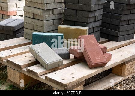 Laying colored concrete paving slabs in the park. Professional workers bricklayers are installing new tiles and paving slabs for sidewalk on leveled s Stock Photo