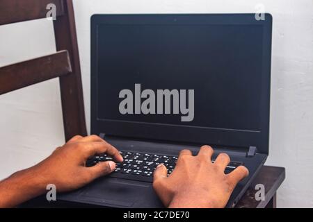 Work from Home - Man's hands using laptop with screen on desk in home interior. Mockup style image of a hand using and touching laptop on table at hom Stock Photo