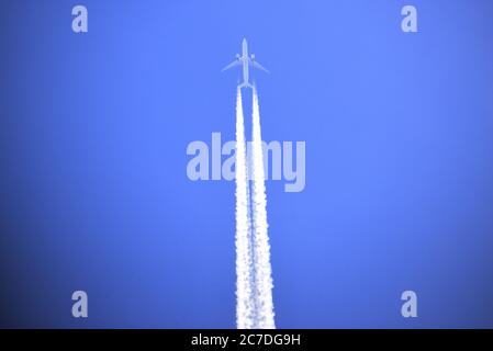 Contrails across a clear blue sky in this photograph of an aircraft over Surrey Stock Photo