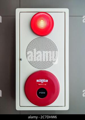 Fire alarm system (fire alarm bell, speaker, siren light) on the white concrete wall of the office building. Stock Photo
