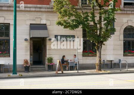 A young man and woman sitting at a table outside Heirloom vegetarian restaurant in Vancouver, British Columbia, Canada Stock Photo