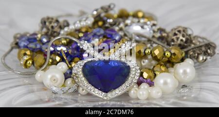 Closeup shot of a beautiful heart shaped blue emerald necklace lying on a pile of jewelry Stock Photo