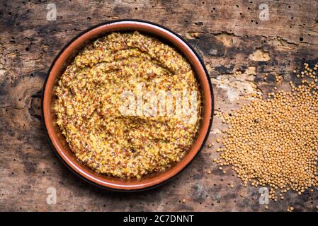 Wholegrain mustard in a wooden bowl on a table tabletop Stock Photo