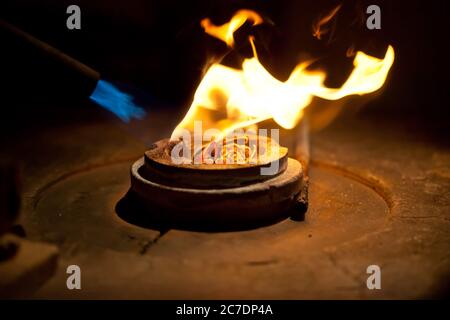 process of casting gold, melting golden metal in furnace with fire for making jewelry Stock Photo