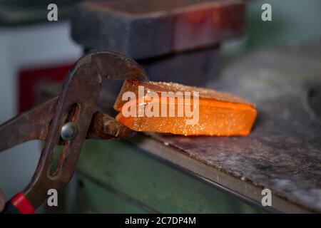 closeup picture of ingots of melt gold, hot shiny metal bars on table and fire furnace on background, nobody Stock Photo