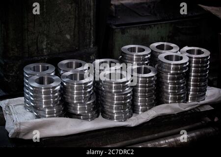 many piles of metallic shiny gears and spare parts for equipment with abstract blurred background, nobody Stock Photo