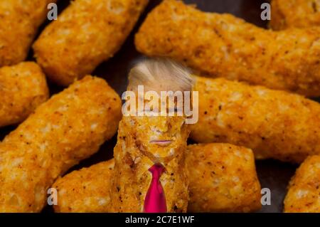 A bunch of orange-colored cheese puffs, like Cheetos.  One has the likeness of Donald Trump, complete with his necktie and wispy hair. Stock Photo