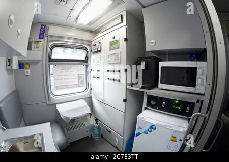Interior of a service compartment of a wagon: conductors seat, window, electrical stove, refrigerator, washbasin, control panel. October 1, 2018. Kiev Stock Photo
