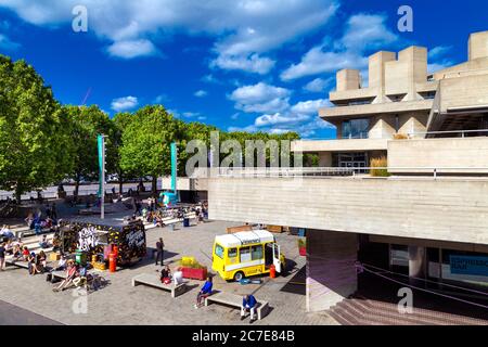 People socialising and food market stalls in front of the National Theatre, Southbank, London, UK