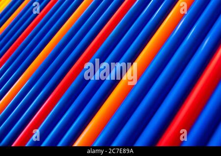 Blue, red, orange pattern plastic tubes straws diagonal background Stock Photo