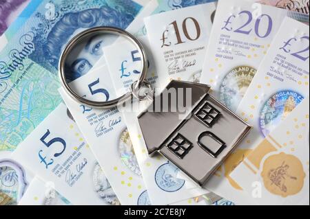 BRITISH MONEY CURRENCY WITH HOUSE KEY RING RE THE ECONOMY COVID 19 CORONAVIRUS CASH JOBS BANKS PENSIONS ETC UK