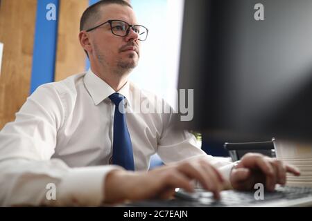Confident and pensive man working with computer at workplace Stock Photo