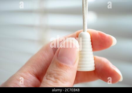 rope blinds with plastic cap in female fingers close-up. Stock Photo