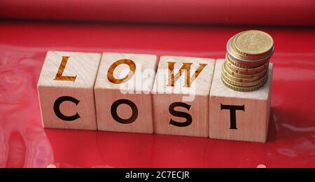 Low cost words on Wooden blocks, down arrow and business team. Unsuccessful business and bankruptcy. Profit decline. Loss of investment. Economic Stock Photo