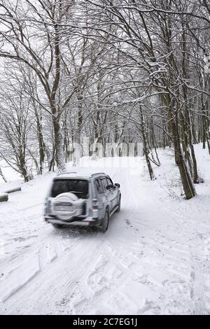 single car on a winter road in the forest. Lots of snow Stock Photo