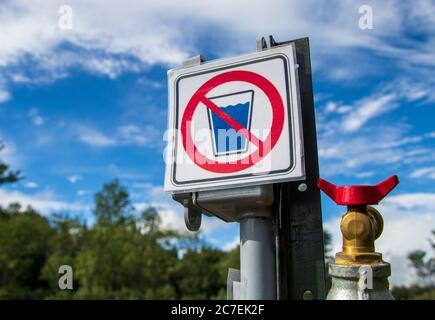 Non-potable water sign on a campground, camping site, view from below and blue sky in background, closeup Stock Photo