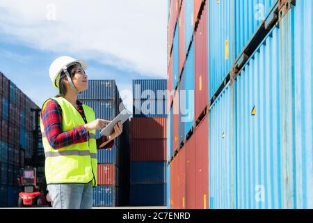 Engineer woman or Foreman manager in container depot working with digital tablet for control and checking industrial container yard for Logistics over Stock Photo