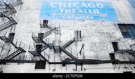 Chicago United States - August 27 2015; Old exteior faded brick wall and blue sign surrounded by fire escape ladders on Chicago Theater building. Stock Photo
