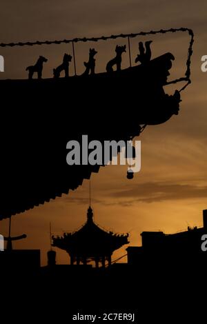 Vertical silhouette of the sunset sky in Xian with a pagoda and traditional roofing Stock Photo