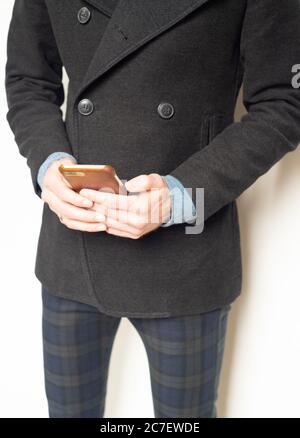 Young man in trendy business casual outfit holding smartphone Stock Photo