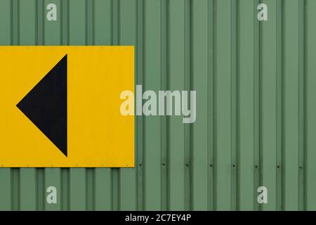 Horizontal shot of a metal wall with an arrow on a yellow square - great for a background Stock Photo