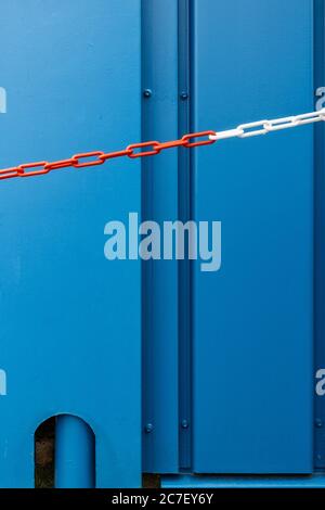 Vertical shot of a blue metal door and a red and white chain - great for a cool wallpaper Stock Photo