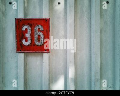Closeup shot of a white wall with the number 36 in a red square - great for wallpaper or background Stock Photo