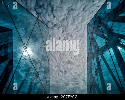 Horizontal low angle shot of the breathtaking cloudy sky between two buildings with glass walls Stock Photo